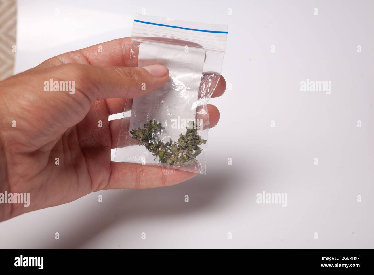 Ein Paket mit illegalem Cannabis in der Hand. Medizinisches Marihuana zur verschreibungspflichtigen Behandlung. Drogenhändler verkauft Marihuana-Süchtige. Stockfoto