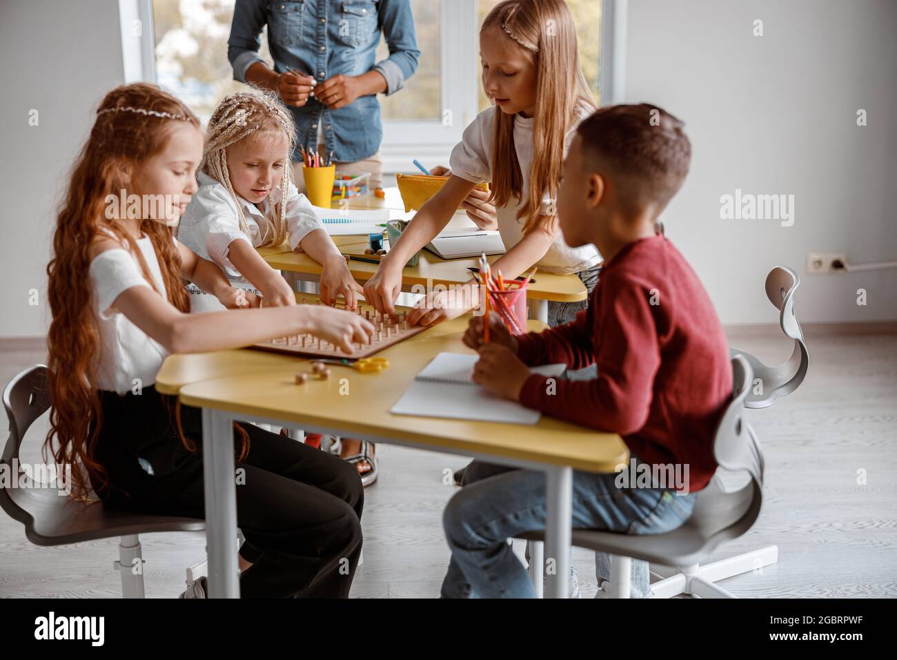 Glückliche Schüler verwenden ein hölzernes Mathetablett Stockfoto
