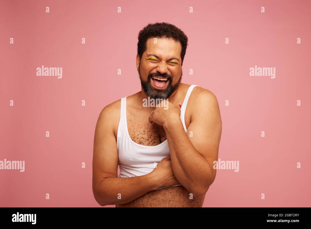 Geschlecht Flüssigkeit Mann trägt Crop Top vor rosa Hintergrund. Genderqueer sieht selbstbewusst und lächelnd aus. Stockfoto
