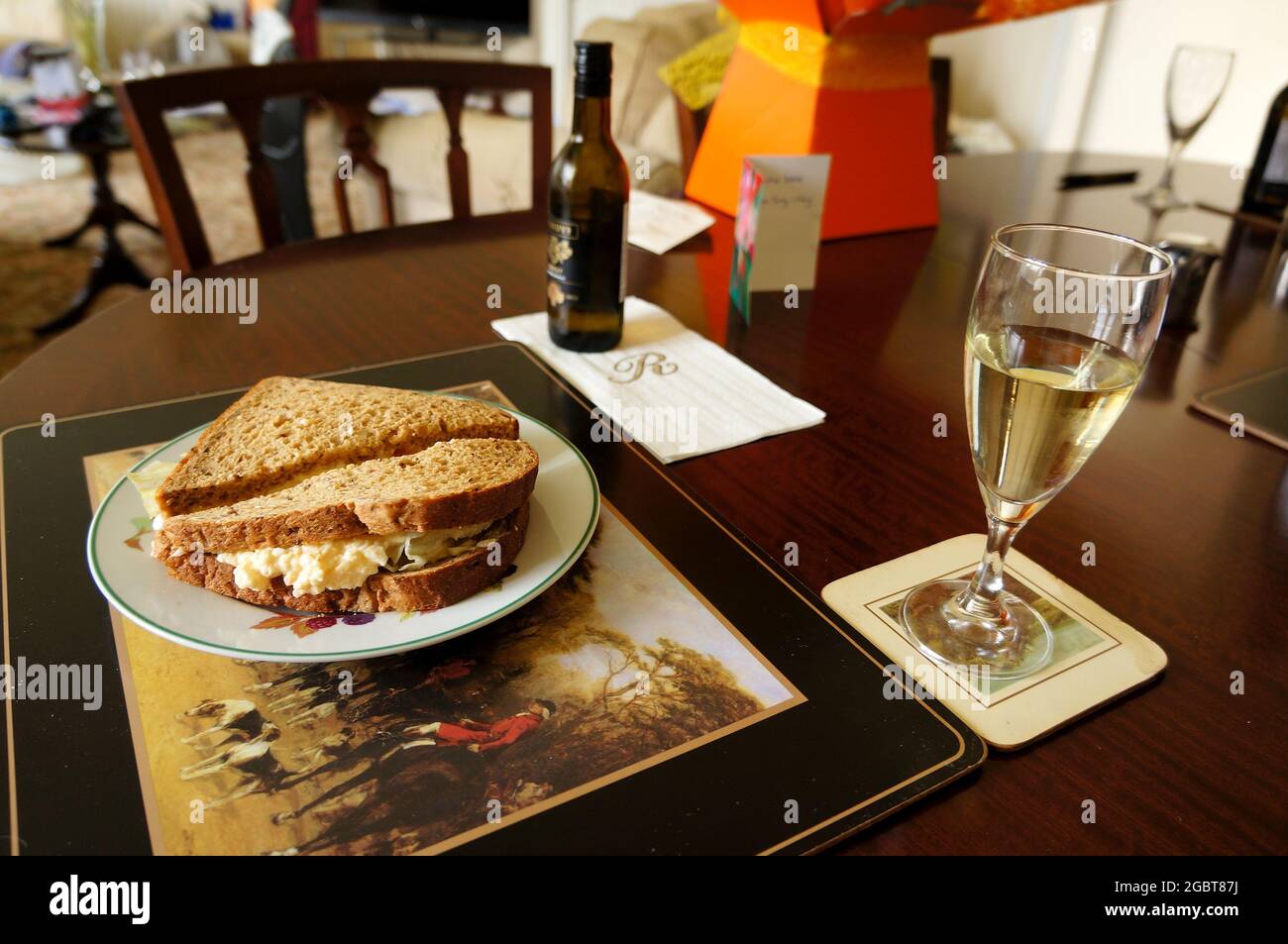 Eiersalat-Sandwich auf einem Teller und ein Glas Wein im Haus mit weichem Hintergrund Stockfoto