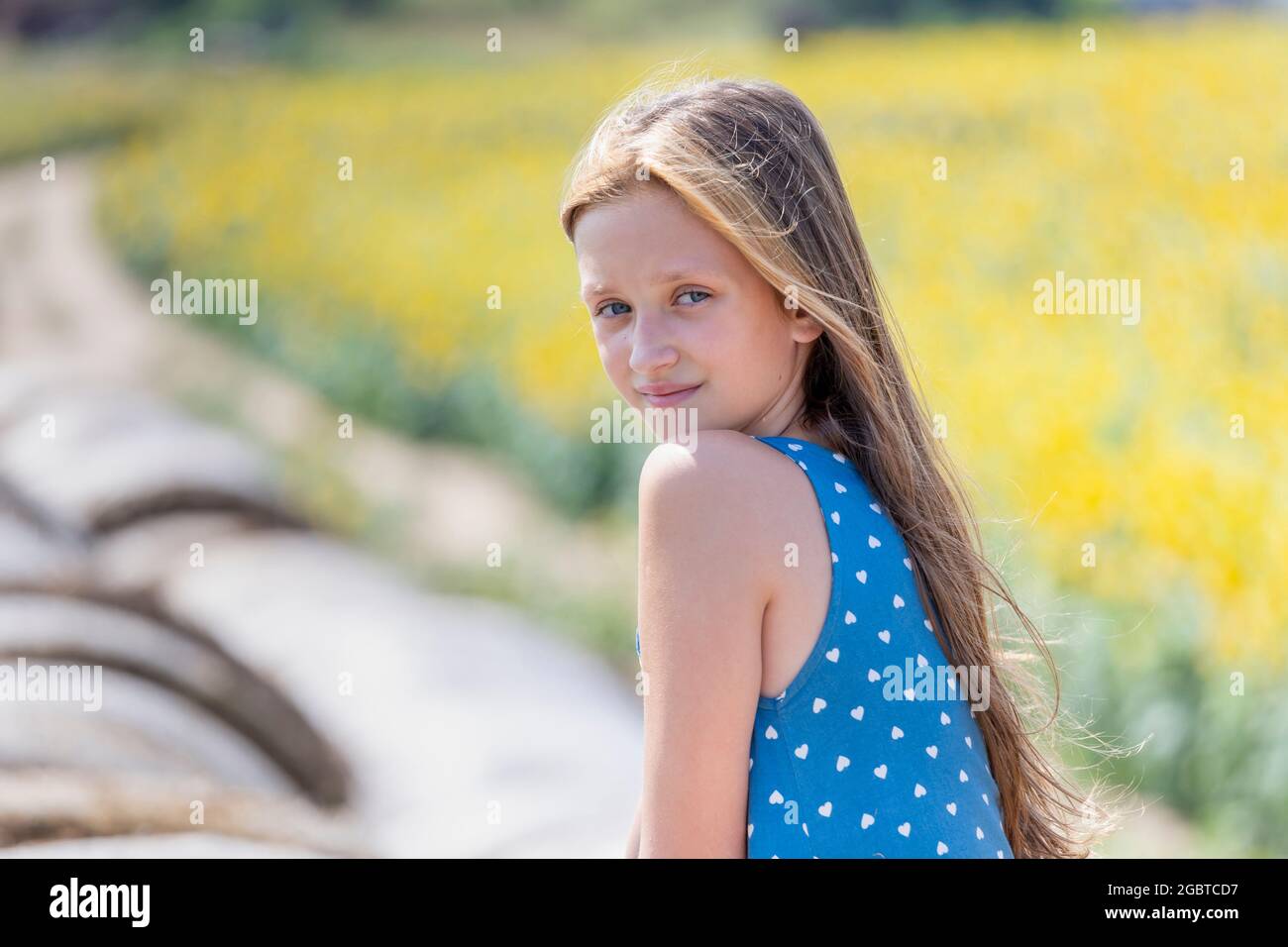 Porträt eines hübschen Mädchen mit langen Haaren auf dem runden Heuballen lächelt die Kamera im Sommer. Generation z. Stockfoto