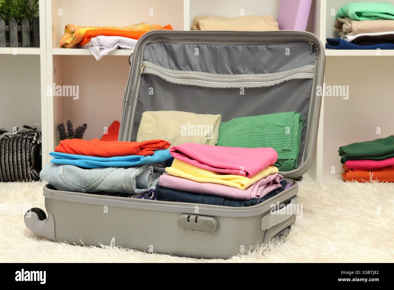 Offener grauer Koffer mit Kleidung im Zimmer Stockfotografie - Alamy