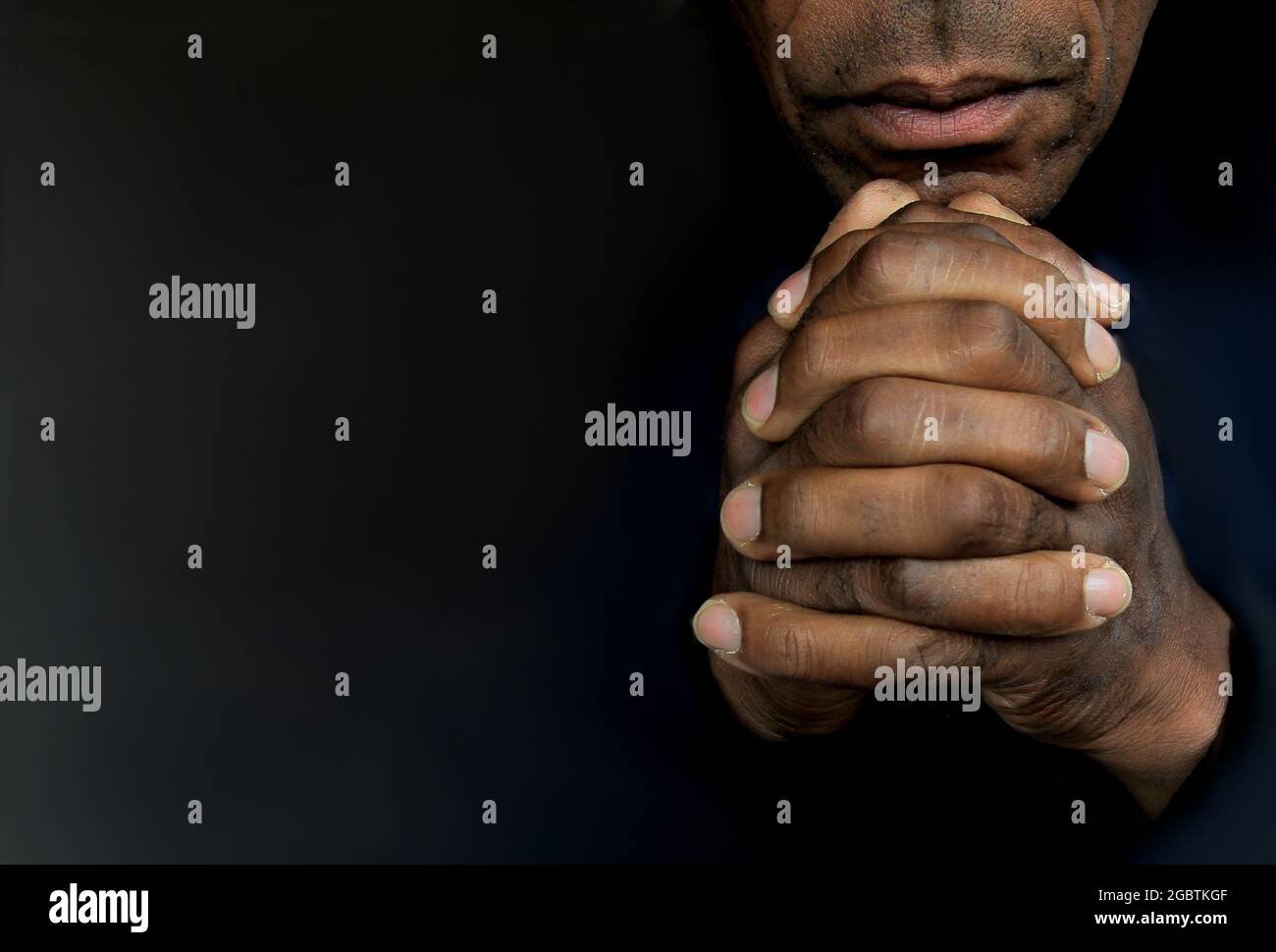 Mann, der mit Händen zu gott betet Karibischer Mann, der mit schwarzem Hintergrund betet Stockfoto Stockfoto