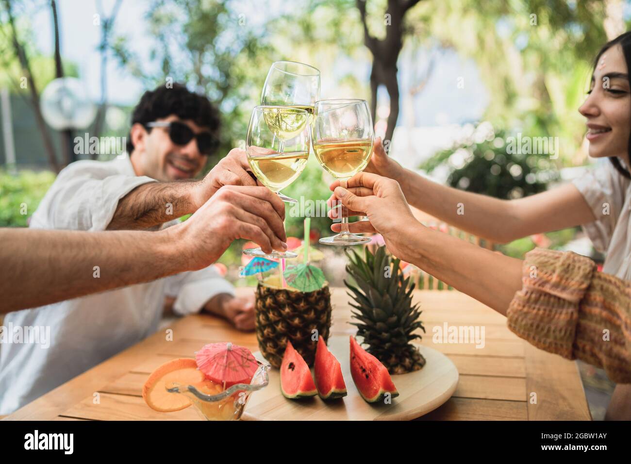 Eine Gruppe junger Freunde, die sich auf der Terrasse treffen und Spaß beim Toasten von Weißwein haben Stockfoto