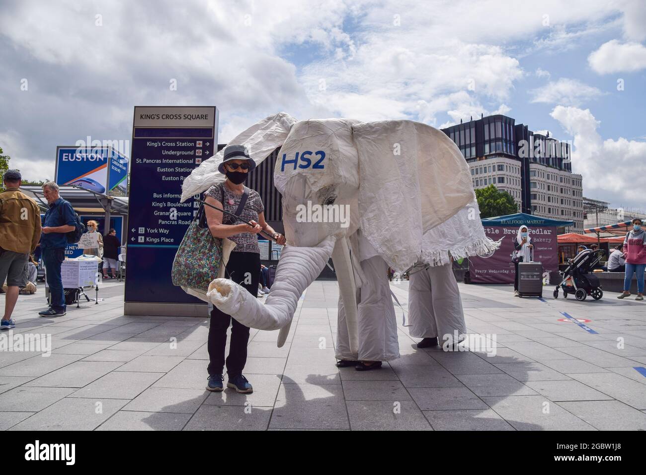 London, Großbritannien. August 2021. Demonstranten, die ein weißes Elefantenkostüm „HS2“ tragen, werden von einem Protestanten vor den Bahnhof geführt. Aktivisten versammelten sich vor dem Bahnhof King's Cross, um gegen das neue Hochgeschwindigkeits-2-Eisenbahnsystem (HS2) zu protestieren, das nach Meinung von Umweltschützern „ökologisch verheerend“ sein wird und den Steuerzahlern £170 Milliarden kosten wird. (Kredit: Vuk Valcic/Alamy Live News) Stockfoto