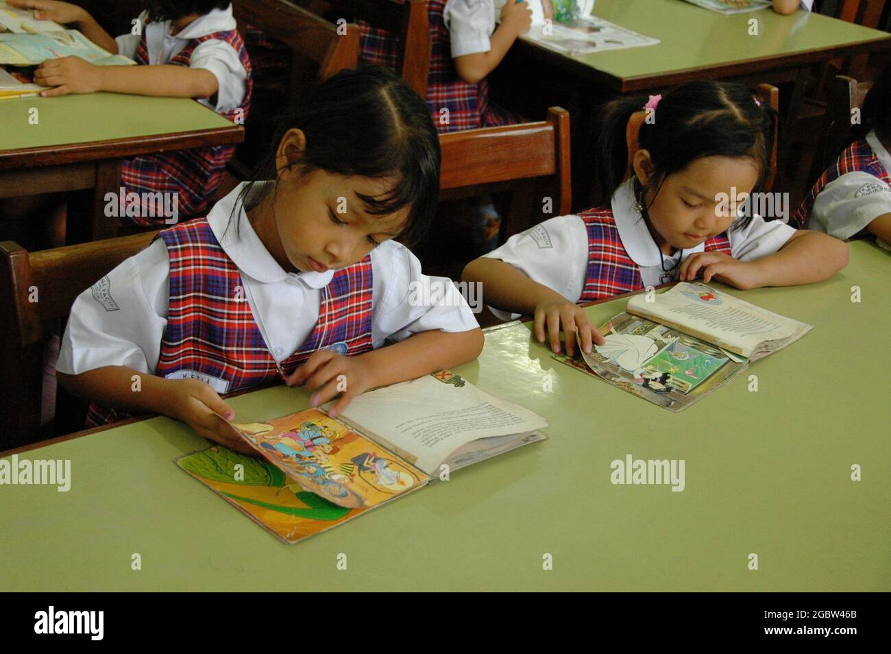 Zwei Kindergartenschüler lesen Bücher auf einem Tisch. Stockfoto