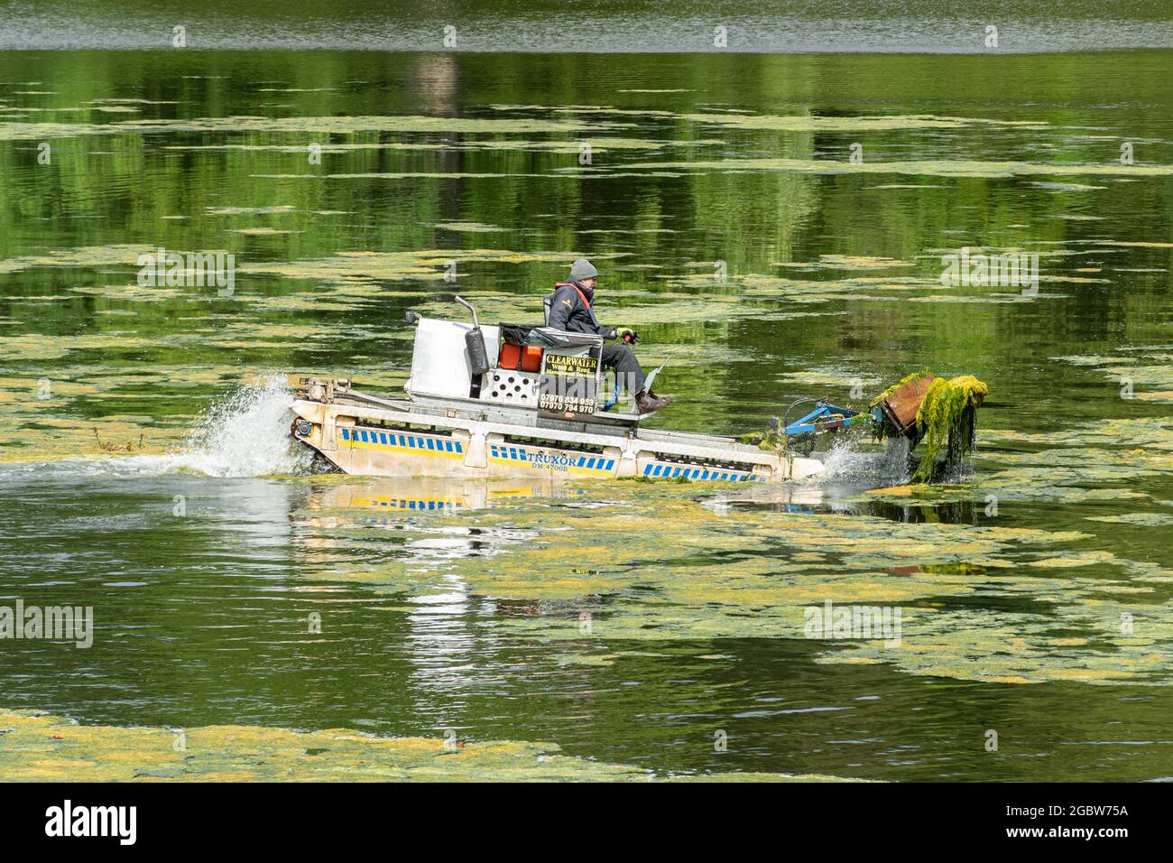 Mann, der an einem Amphibienfahrzeug arbeitet, das als truxor bezeichnet wird und das Teichunkraut oder Algen aus einem See entfernt, Großbritannien Stockfoto