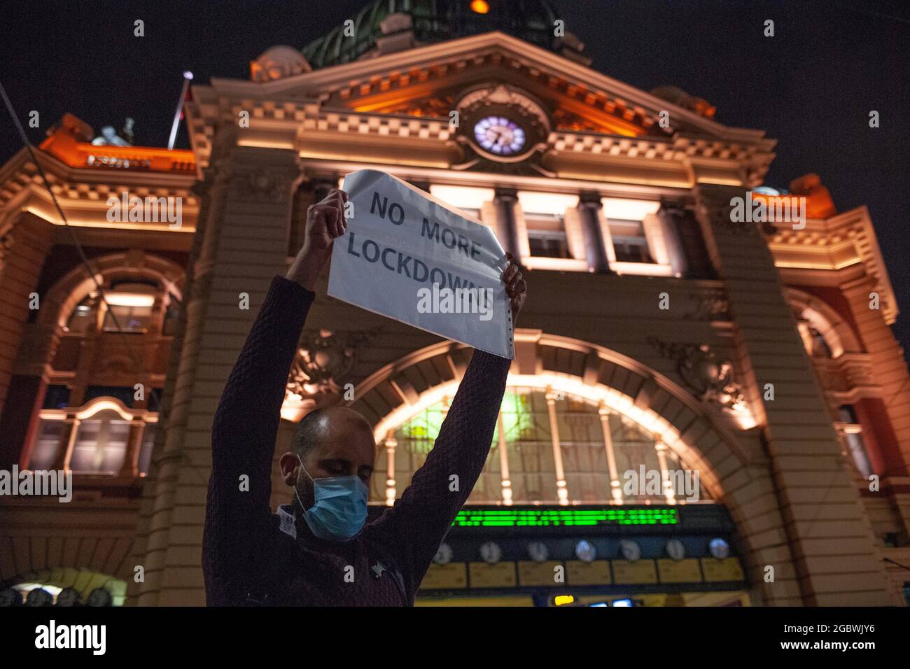 Melbourne, Australien. August 2021. Ein heruntergetretender Protestler hält ein Schild mit der Aufschrift „KEINE SPERRUNGEN MEHR“ vor der Flinders Street Station. Unglücklich über die jüngste Ankündigung, dass Victorias sechste Sperre später in dieser Nacht beginnen würde, fand ein Schnellprotest statt, der über die 20:00 Uhr-Sperrzeit hinausging. Quelle: Jay Kogler/Alamy Live News Stockfoto