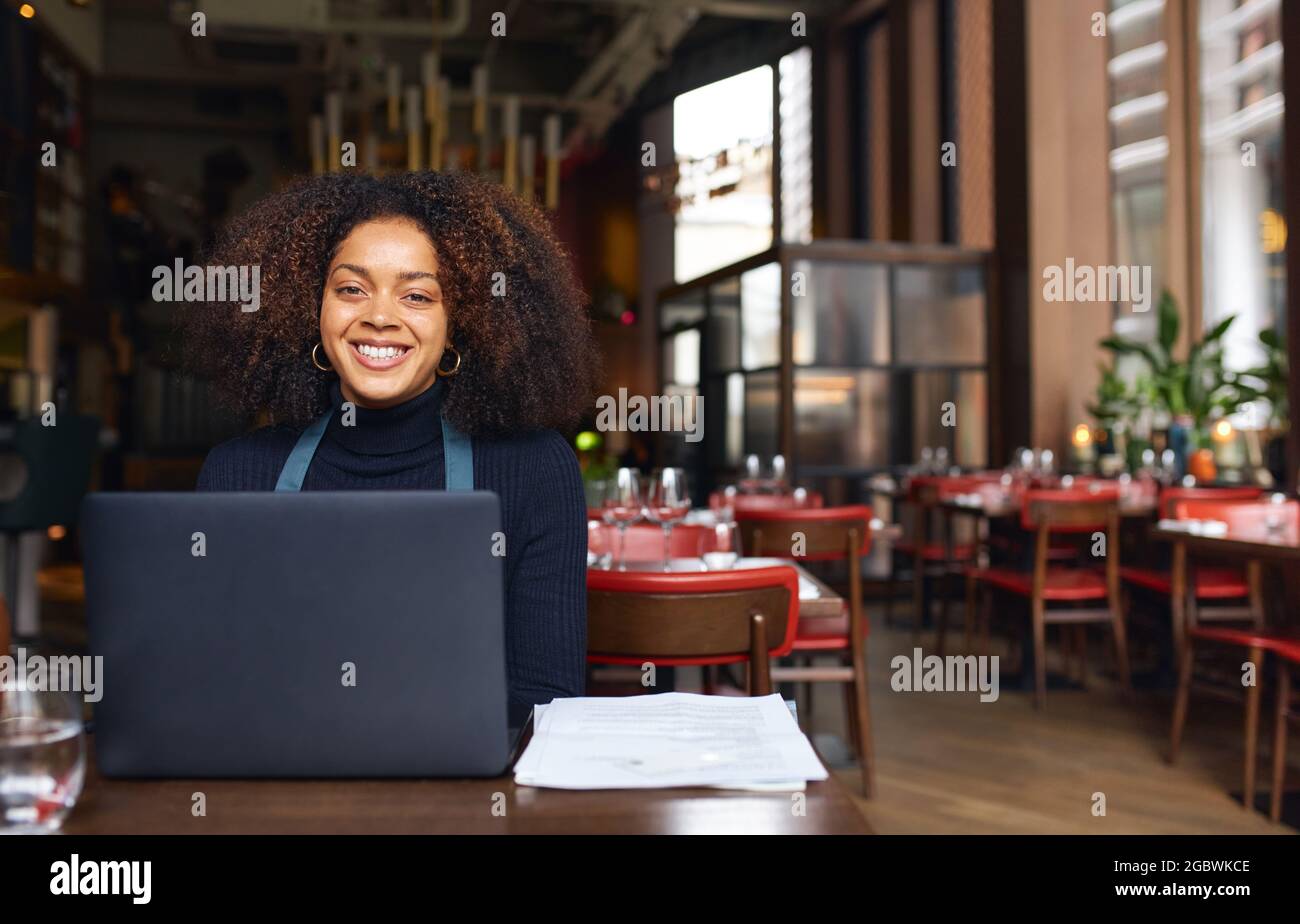 Porträt des fröhlichen Restaurantbesitzers mit Laptop Stockfoto