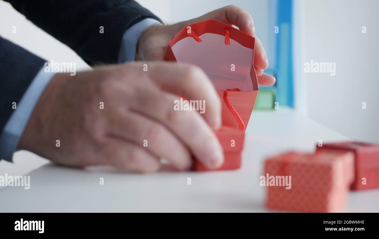 Bereiten Sie ein Geschenk für einen Geburtstag in einem Geschenkeladen vor, und legen Sie kleine Geschenkschachteln in eine farbige Papiertüte. Stockfoto