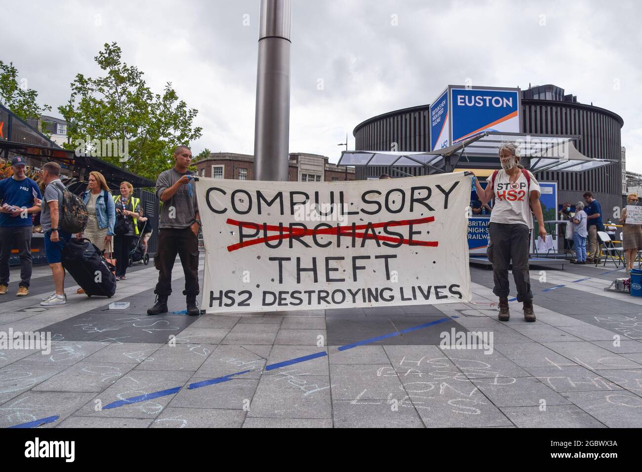 London, Großbritannien. August 2021. Demonstranten halten während des Stop HS2 Protestes ein Anti-HS2-Banner neben einem Euston HS2 Informationsstand.Aktivisten versammelten sich vor der King's Cross Station, um gegen das neue Hochgeschwindigkeits-2-Eisenbahnsystem (HS2) zu protestieren, das Umweltschützer als "ökologisch verheerend" bezeichnen und Steuerzahler £170 Milliarden kosten werden. (Foto: Vuk Valcic/SOPA Images/Sipa USA) Quelle: SIPA USA/Alamy Live News Stockfoto