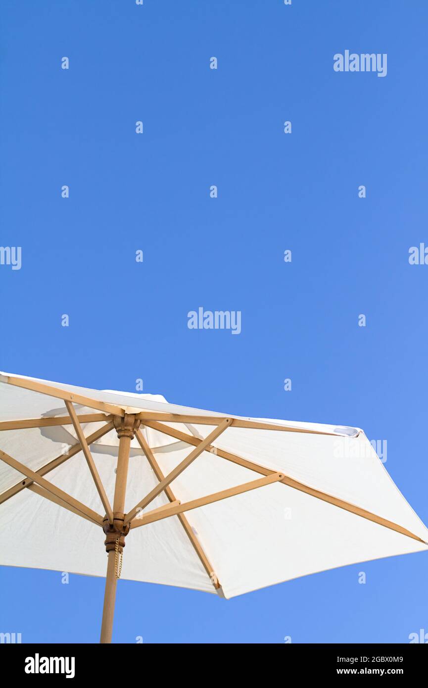 Weißer Sonnenschirm aus Baumwolle und Holz isoliert gegen EINEN Clear Blue Sky England Stockfoto