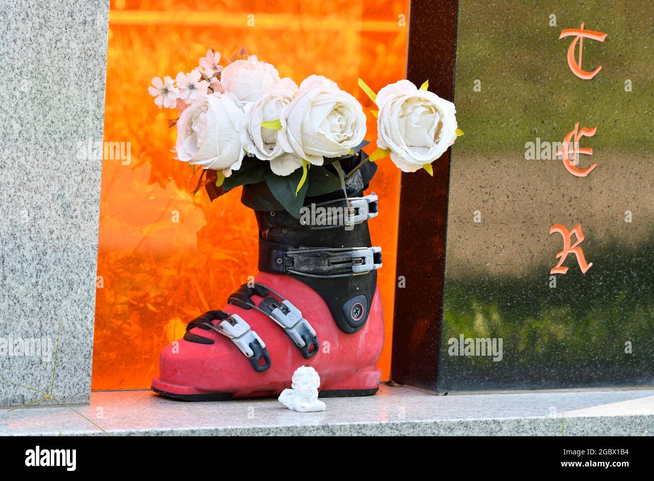 Wien, Österreich. Wiener Zentralfriedhof. Skistiefel mit Plastikblumen auf einem Grabstein Stockfoto