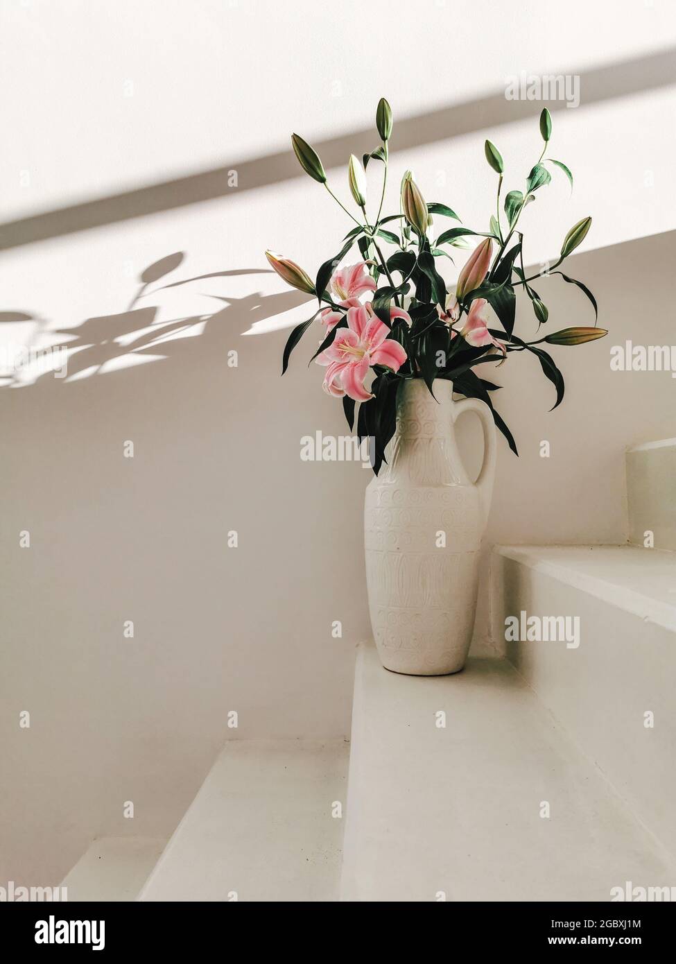 Weiße Vase mit Blumen auf der weißen Treppe Stockfoto