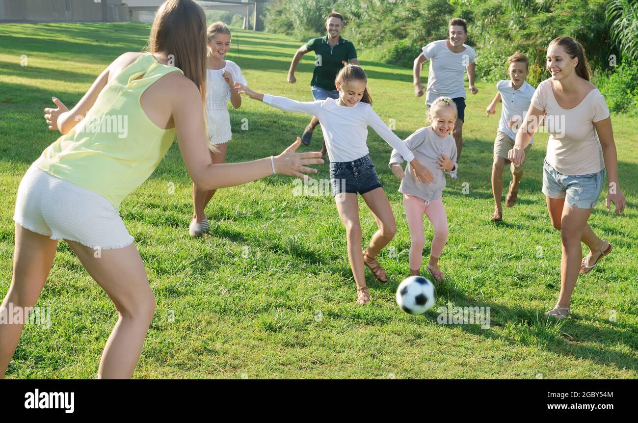 Zwei freundliche Familien mit Kindern, die im Sommer in der Natur Fußball spielen Stockfoto