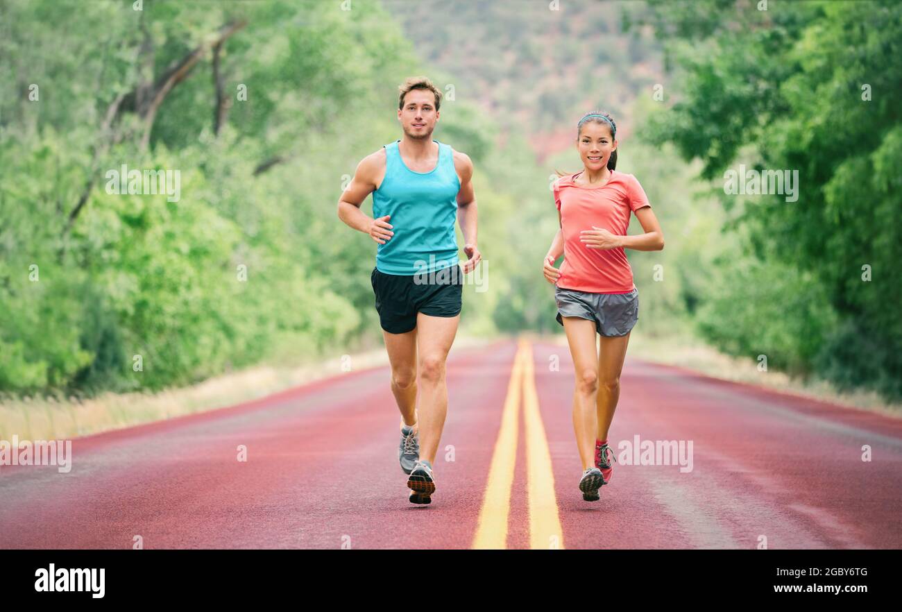 Sommerlauf Mann und Frau Läufer Paar fit Menschen Joggen Training für Marathon. Junge Athleten auf schnellem Cardio-Joggen-Workout auf der Sommerparkstraße Stockfoto