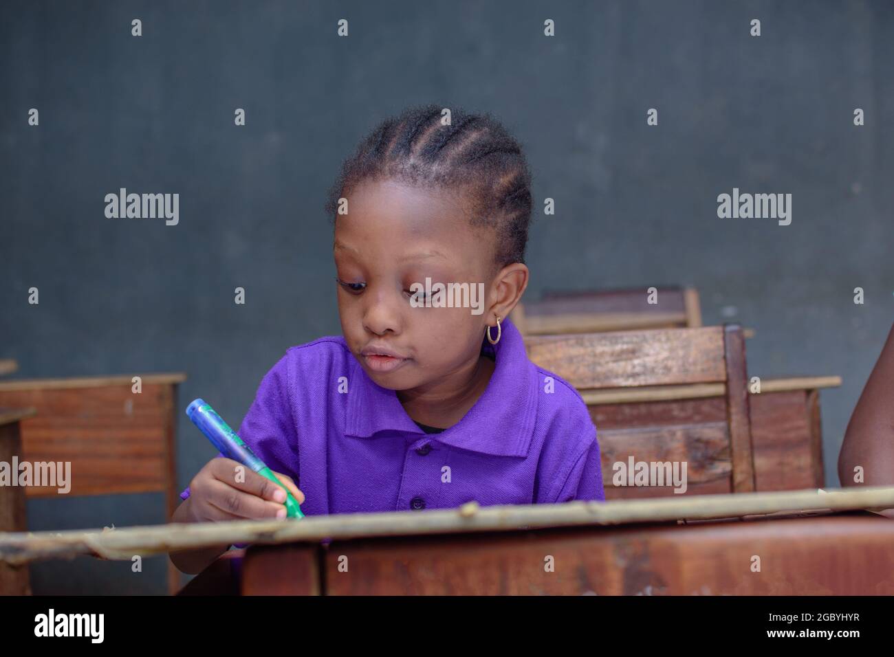 Afrikanisches Mädchen, Schülerin oder Schülerin, die sich in einem Klassenzimmer hinsetzt und schreibt, während sie in ihrer Schule, Ausbildung und Karriere für hervorragende Leistungen studiert Stockfoto