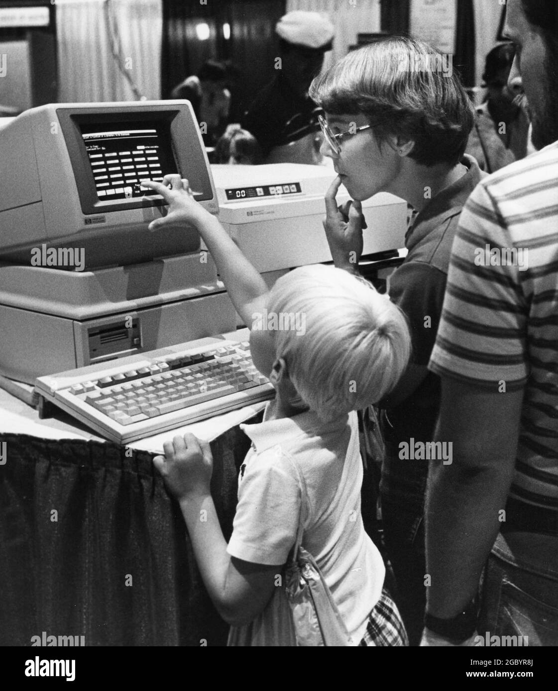 Austin, Texas, USA, um 1986: Der junge Mann schaut sich den neuen PC an, während seine Mutter auf der Messe für Technologiekonventionen schaut. ©Bob Daemmrich Stockfoto