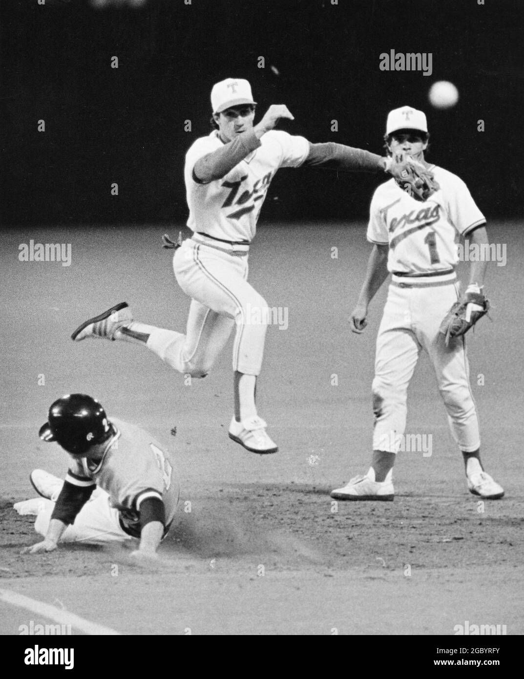 Austin Texas USA um 1982: Action zwischen dem Baseballteam der University of Texas und den Gegnern auf dem Heimfeld der UT; Shortstop wirft den Ball in die erste Basis, während der Läufer in die zweite Basis gleitet. ©Bob Daemmrich Stockfoto