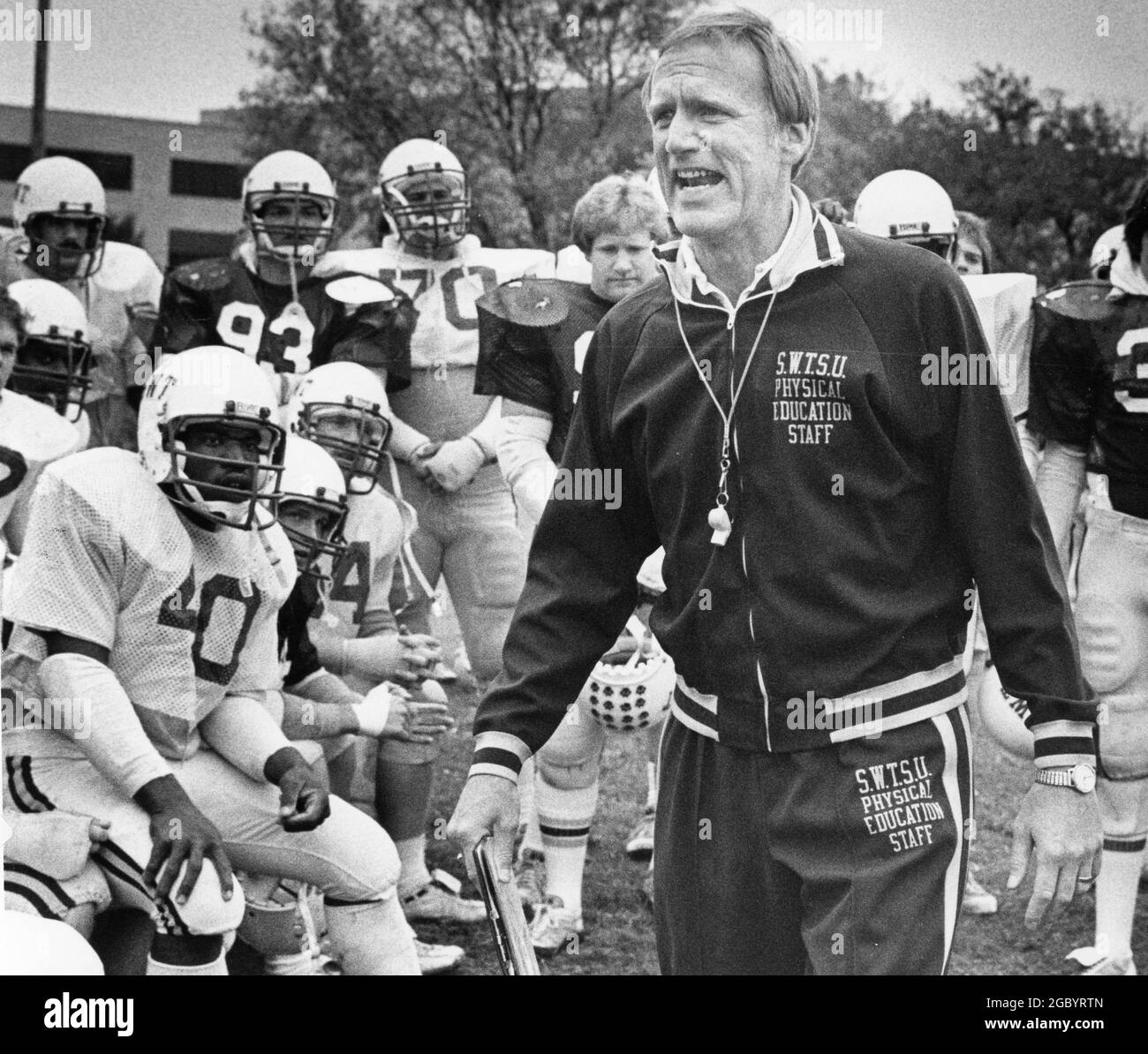 San Marcos Texas USA, um 1982: Fußballtrainer Jim Wacker von der Southwest Texas State University ruft seinen Spielern während des Trainings Anweisungen zu. ©Bob Daemmrich Stockfoto