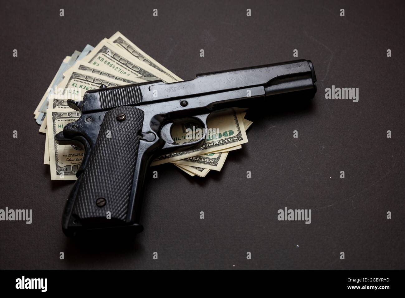 Kriminelles Geld, Mafia- und Korruptionskonzept, Kriminalkonzept, Pistolenhandgun 9 mm und amerikanische Dollar-Banknoten auf schwarzem Hintergrund. Stockfoto