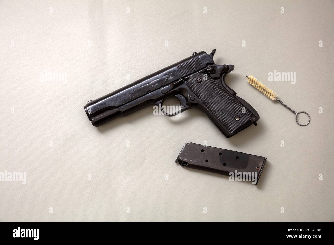 Pistole 9 mm Wartung auf grauem Hintergrund. Schwarze Metallwaffe, Magazin und Reinigungsstange. Seitenansicht von oben Stockfoto