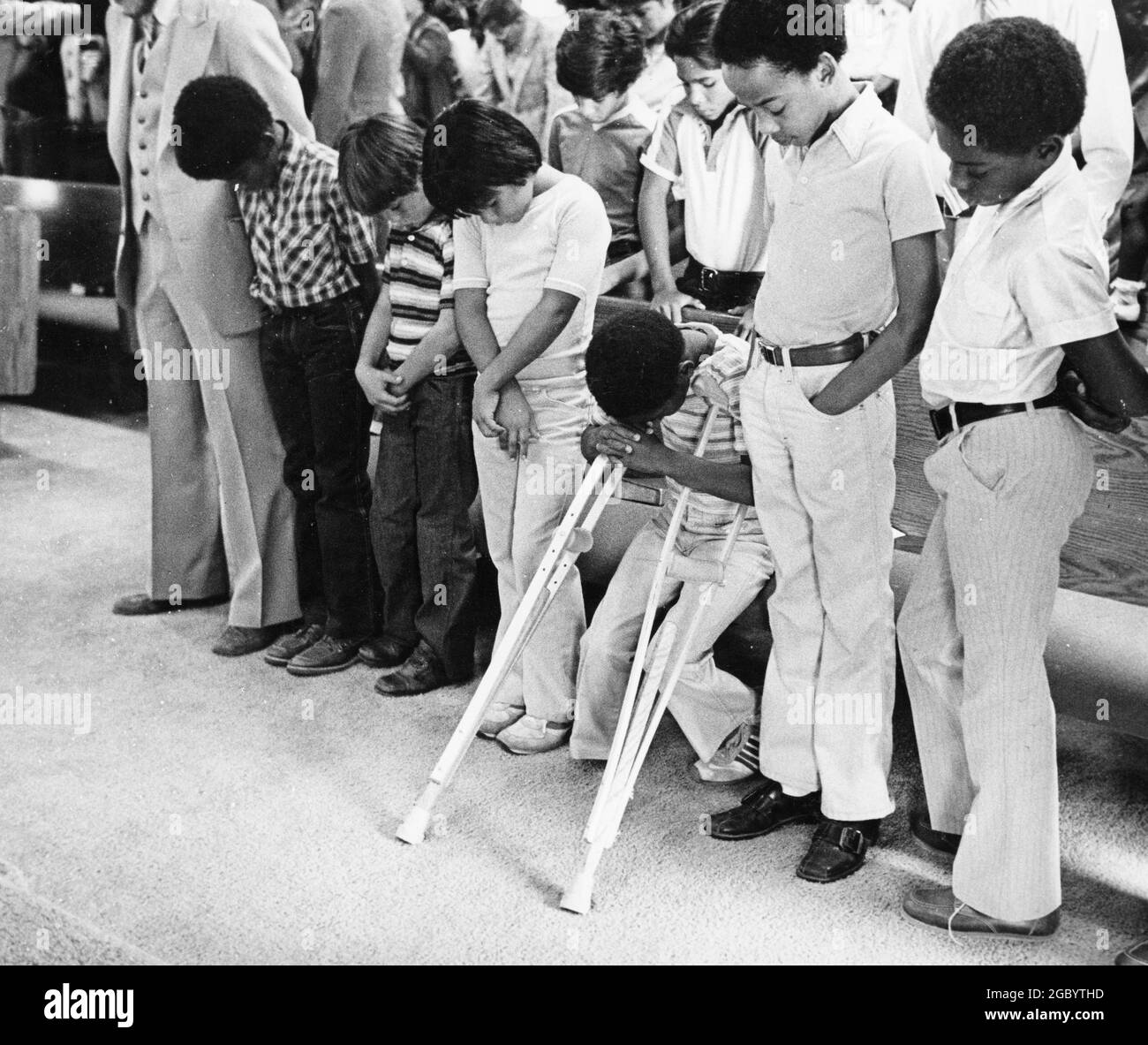 Austin Texas USA, 1984: Patrick Skeaton, Junge der 4. Klasse mit Spia bifida, dessen Bein im Vorjahr amputiert wurde, lehnt sich während des Baptistengottesdienstes mit Familie und Freunden an seine Krücken. ©Bob Daemmrich Stockfoto