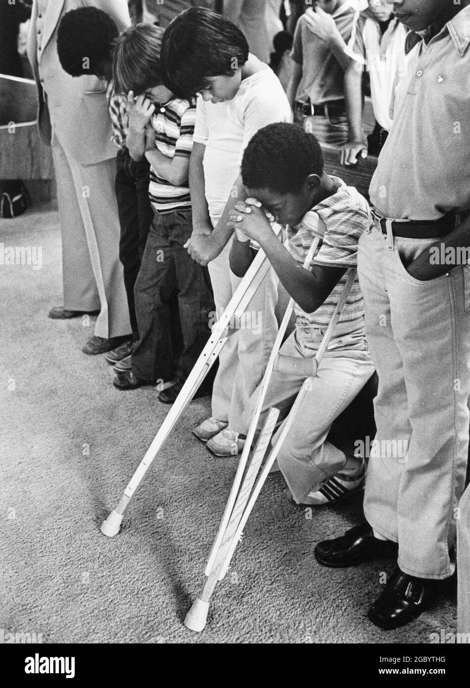 Austin Texas USA, 1984: Patrick Skeaton, Junge der 4. Klasse mit Spia bifida, dessen Bein im Vorjahr amputiert wurde, lehnt sich während des Baptistengottesdienstes mit Familie und Freunden an seine Krücken. ©Bob Daemmrich Stockfoto