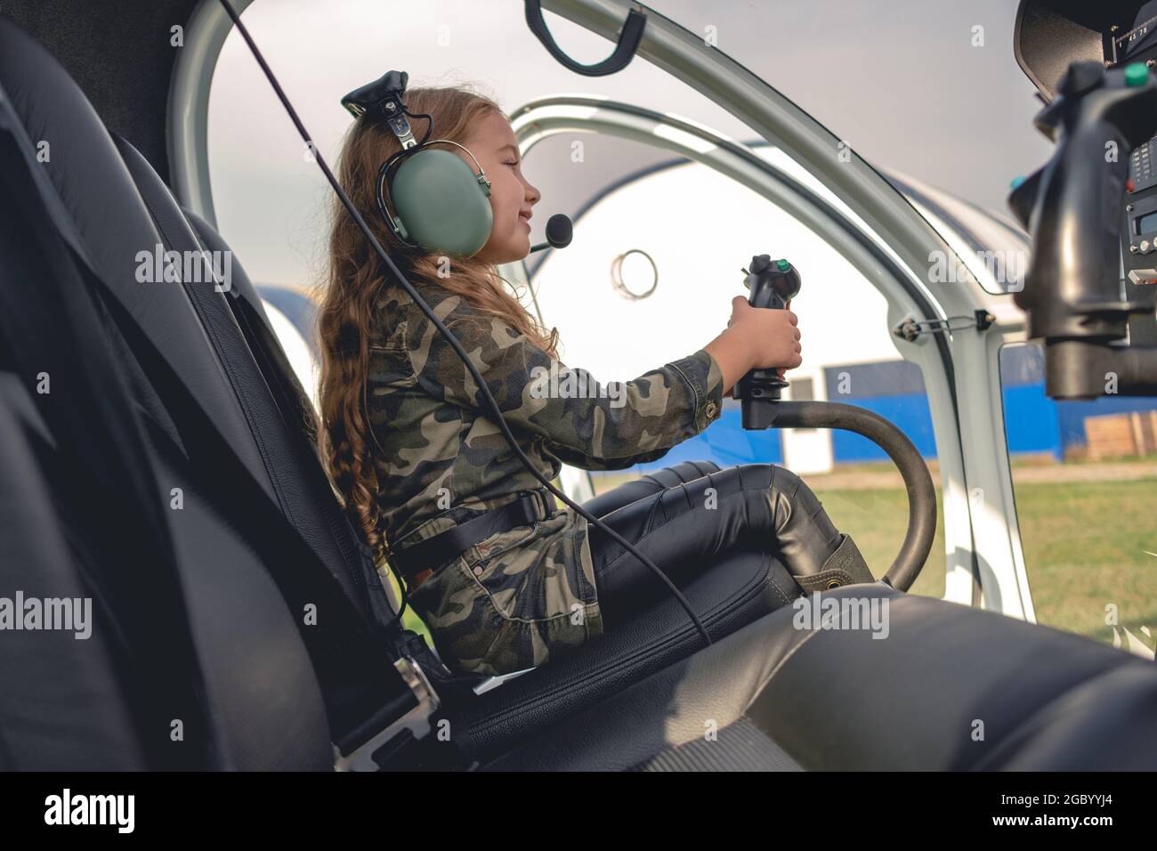 Fröhliches Mädchen in Pilot-Headset sitzt im Hubschrauber-Cockpit Stockfoto