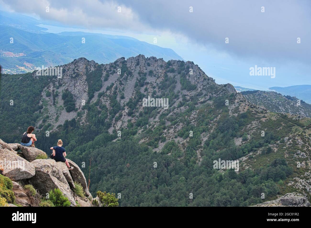 Zwei junge Frauen sitzen am Rande des Felsens Stockfoto