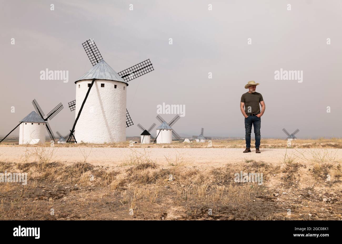Ein Mann mit Cowboyhut und Windmühlen auf dem Land Stockfoto