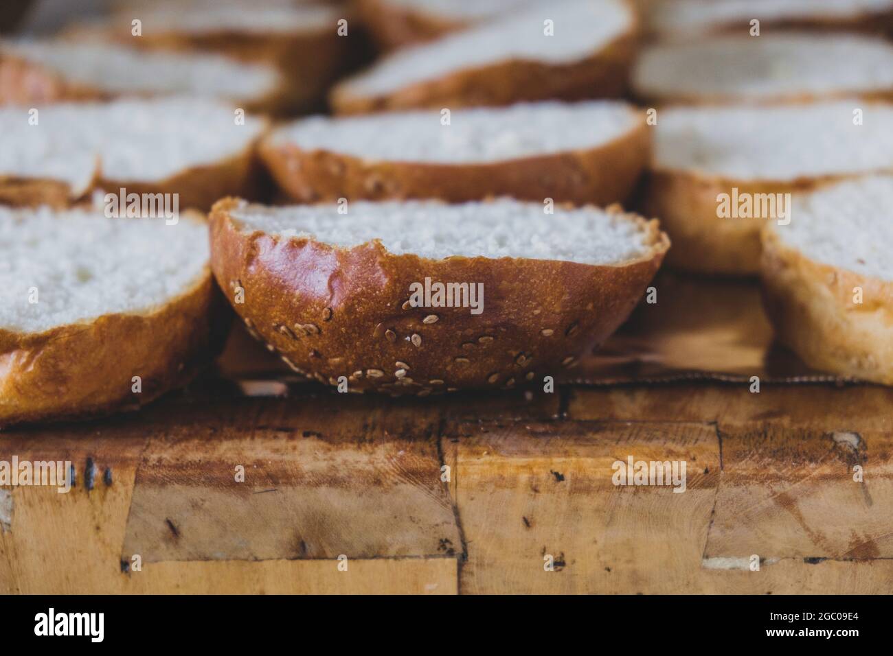 Burger-Brot auf ein Schneidebrett gelegt. Schneidebrett mit Brotscheiben mit Sesamsamen für die Herstellung von Burgern. Sandwiches mit Sesam für gemahlenen Mea Stockfoto