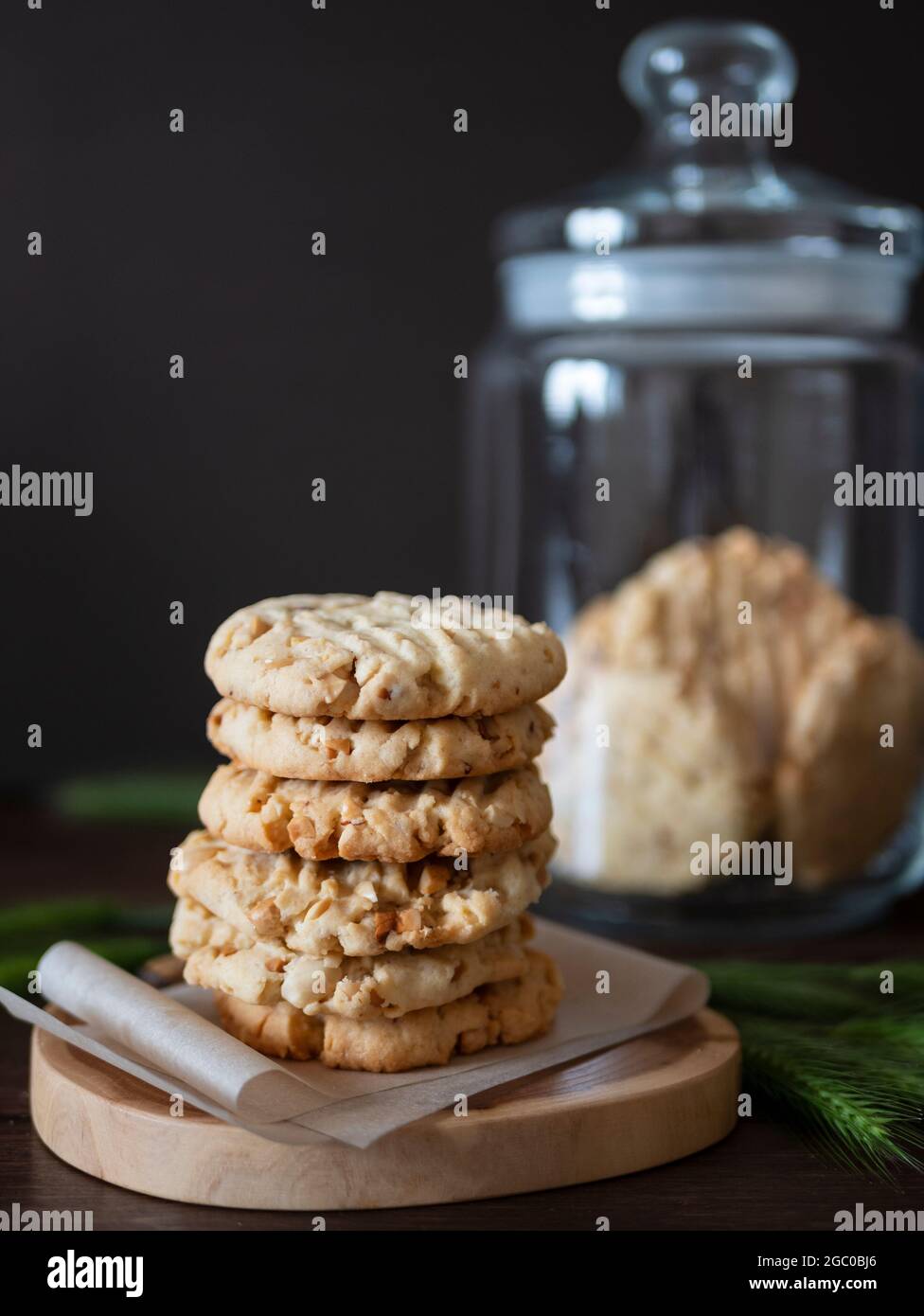 Hausgemachte Nuss-Kekse auf einem Holzbrett, Spikelets und ein Glas Keks auf dem Hintergrund. Hochformat Stockfoto