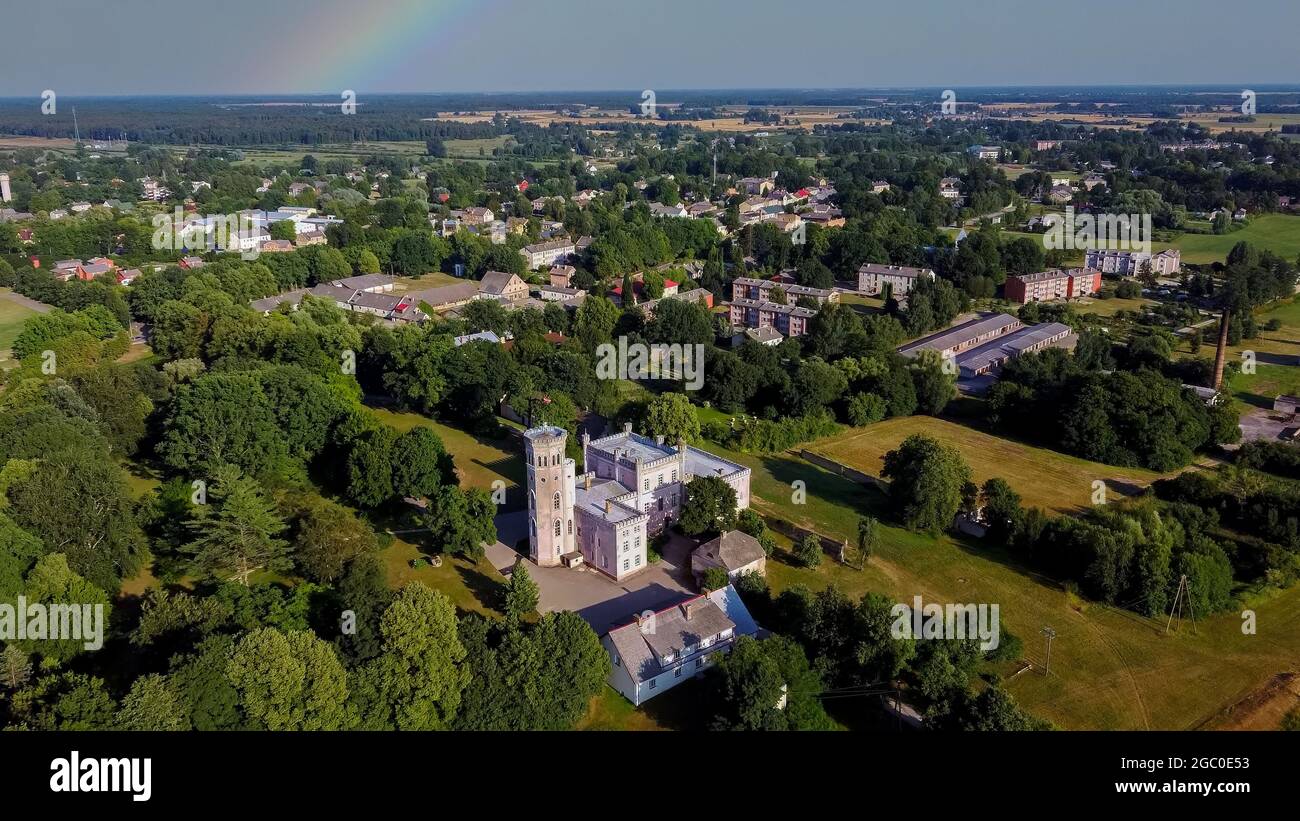 Vecauce Manor in Lettland Luftaufnahme des Rosa Schlosses durch den Park. Burgturm von Vecauce mit einer fliegenden lettischen Flagge. Blick Von Oben. Stockfoto