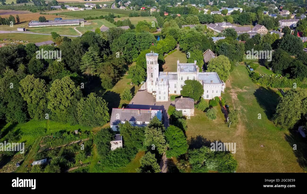 Vecauce Manor in Lettland Luftaufnahme des Rosa Schlosses durch den Park. Burgturm von Vecauce mit einer fliegenden lettischen Flagge. Blick Von Oben. Stockfoto