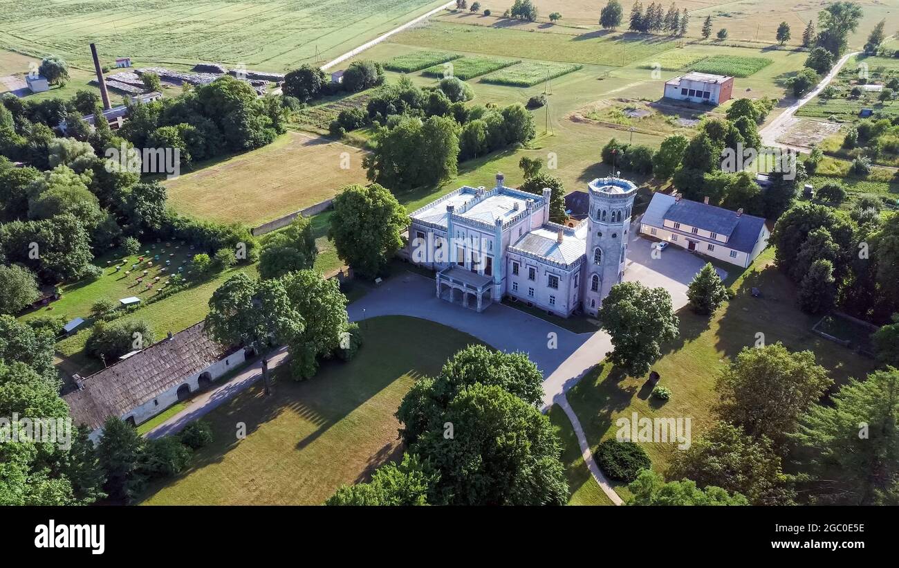 Vecauce Manor in Lettland Luftaufnahme des Rosa Schlosses durch den Park. Burgturm von Vecauce mit einer fliegenden lettischen Flagge. Blick Von Oben. Stockfoto