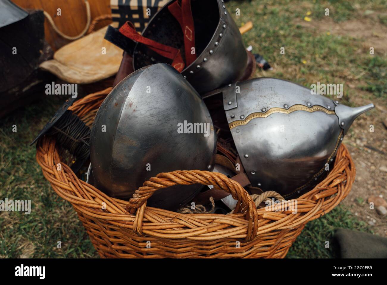 Nahaufnahme von alten mittelalterlichen Ritter Metallhelmen im Korb, die  draußen auf den Boden gelegt wurden Stockfotografie - Alamy