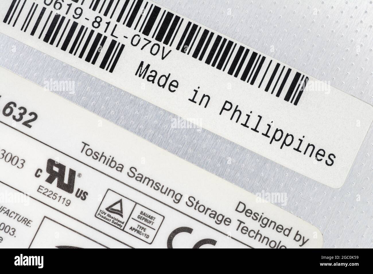 Papieretiketten auf der Rückseite des Toshiba-Samsung hergestellten herausnehmbaren DVD-Writer-Laptops mit dem Etikett Made in the Philippines. Für das Offshoring von Teilen, Außenhandel. Stockfoto