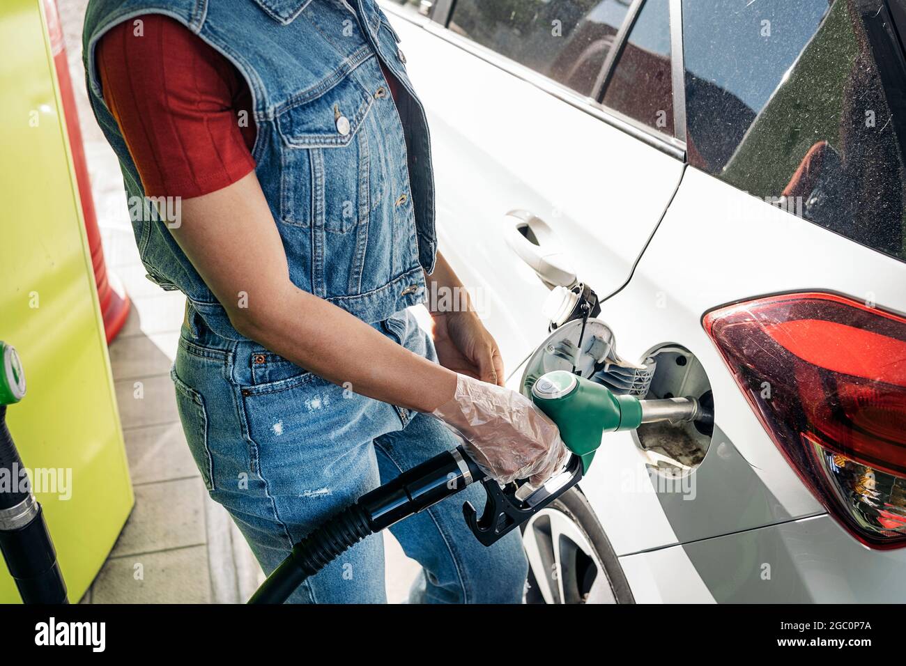 Unerkannte afrikanische Frau, die an der Tankstelle Plastikhandschuhe trug und ihr Auto mit Benzin füllte. Stockfoto