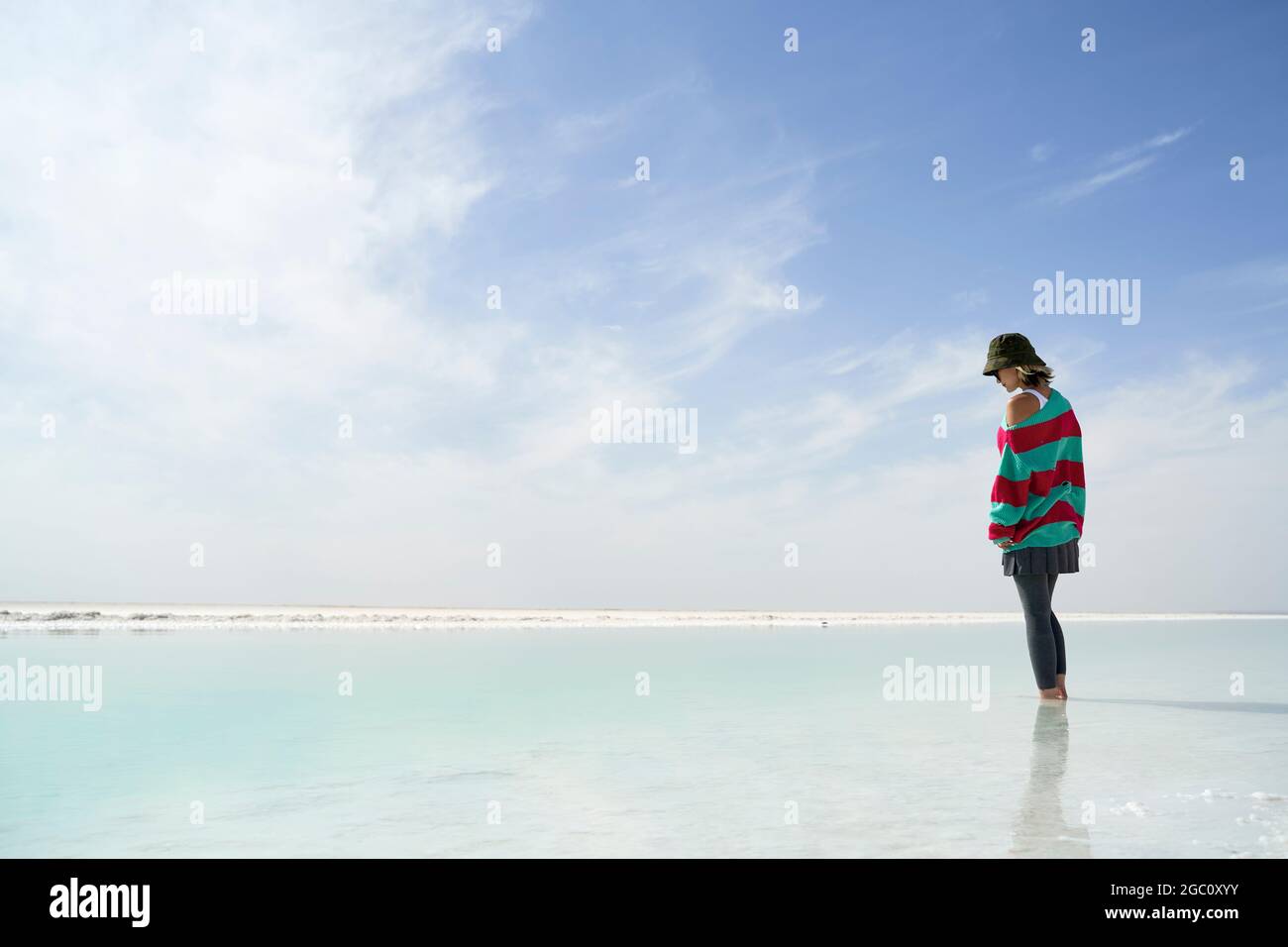 asiatische Frau, die in einem Salzsee steht und auf das Wasser schaut Stockfoto