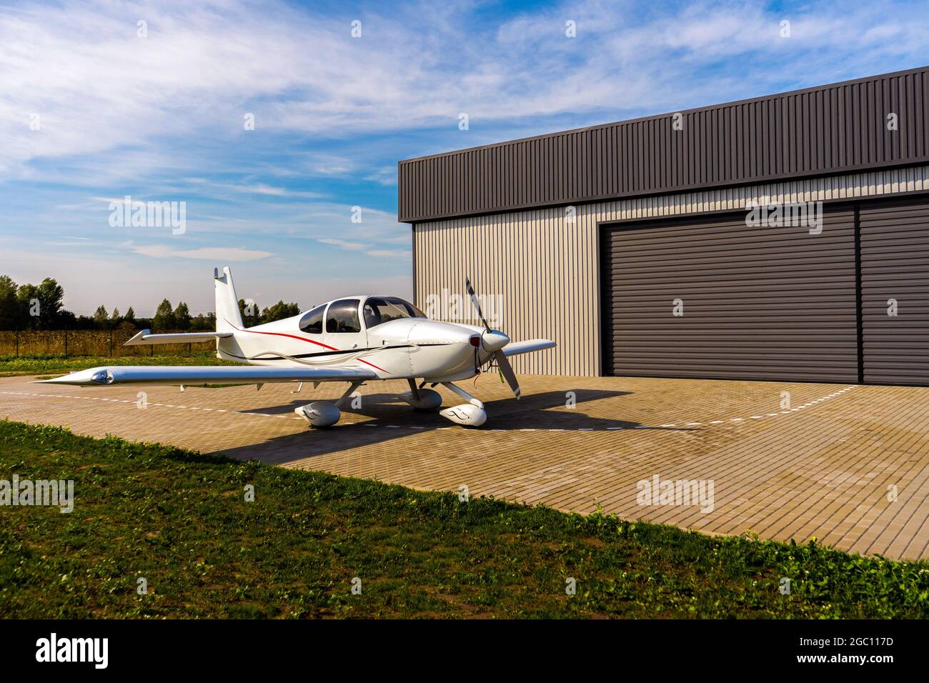 Ein kleines weißes Privatflugzeug vor dem Flug in der Nähe des Hangars. Stockfoto