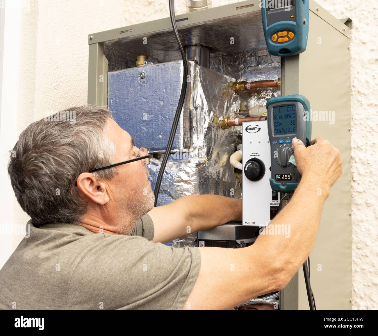 Kesselinstallationsingenieur, der einen mit Heizöl befeuerten Kessel im Freien mit einem Rauchgasanalysator in Betrieb genommen hat. Stockfoto