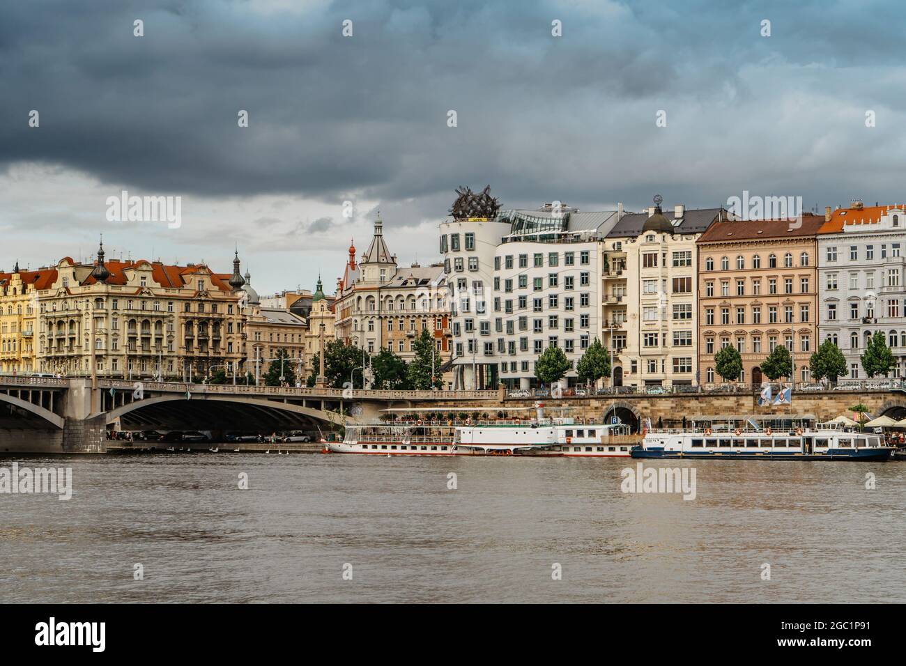 Prag, Tschechische Republik.erstaunliche Aussicht auf das berühmte Tanzende Haus und Rasin Embankment.Riverfront bunte Gebäude, Brücke über Moldau, Boote. Stockfoto