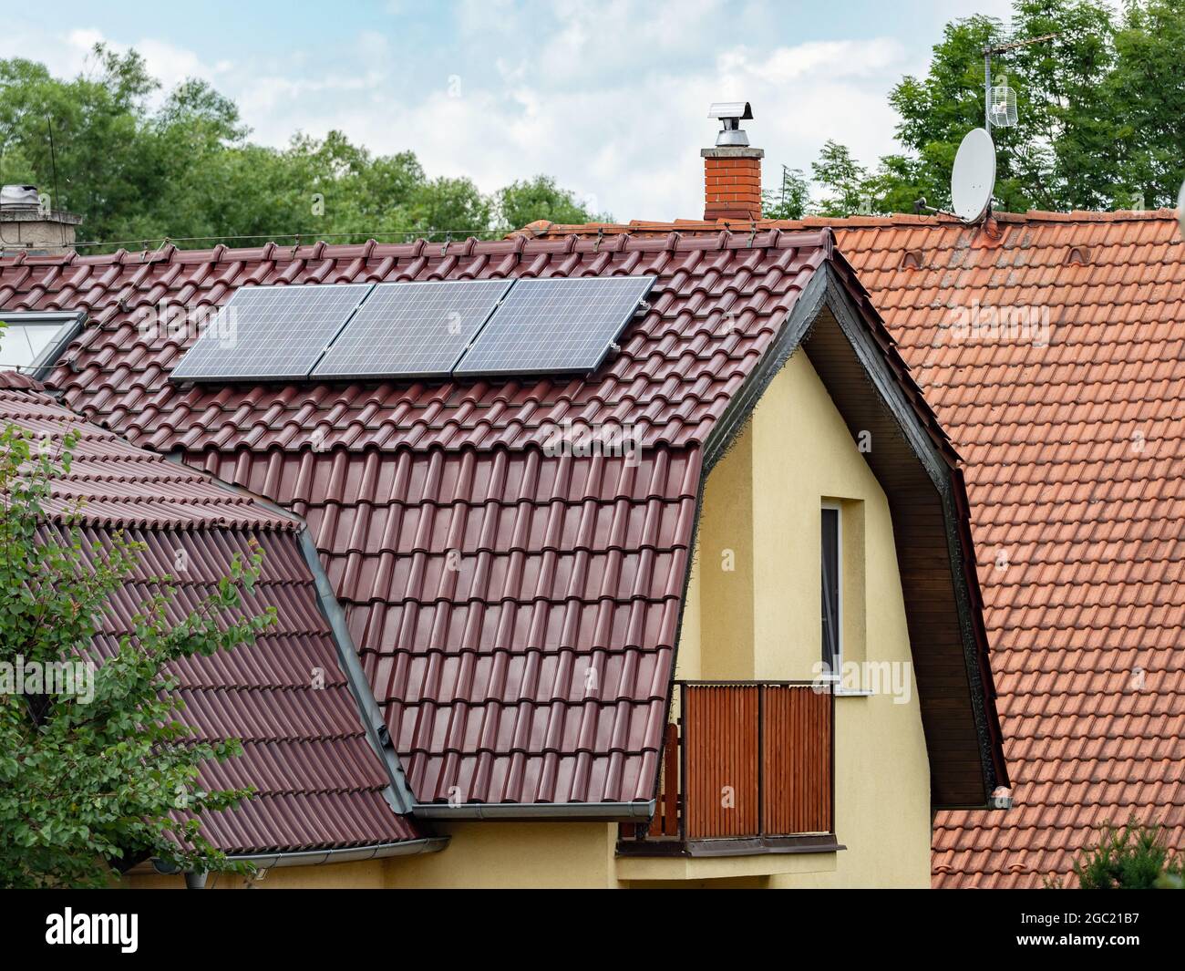 Elektrische Solarzellen auf dem Ziegeldach des Familienhauses. Die isolierte Fassade des Hauses verschlechtert seine Energieintensität. Stockfoto