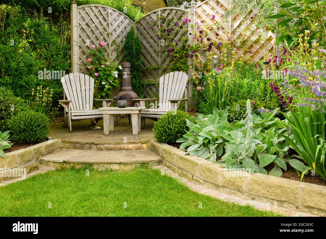 Schöner, farbenprächtiger Garten (modernes Design, geschwungene Begrenzungslinien, dekorative Chiminea, Zaun, Terrasse) - Yorkshire England Großbritannien Stockfoto