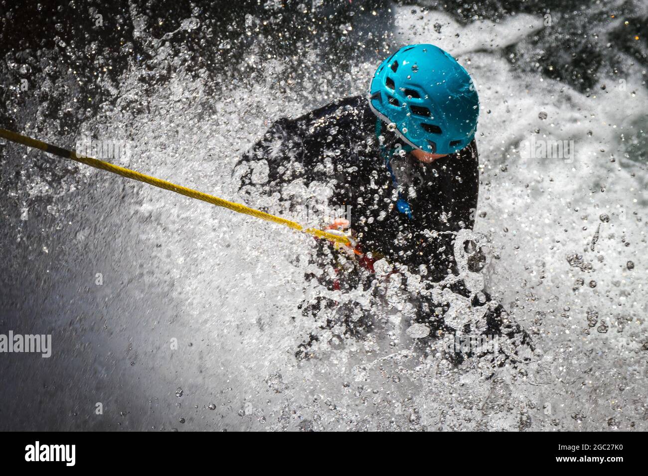 Person mit einem blauen Helm Rafting in Korsika, Frankreich mit Wasser spritzt alles Stockfoto