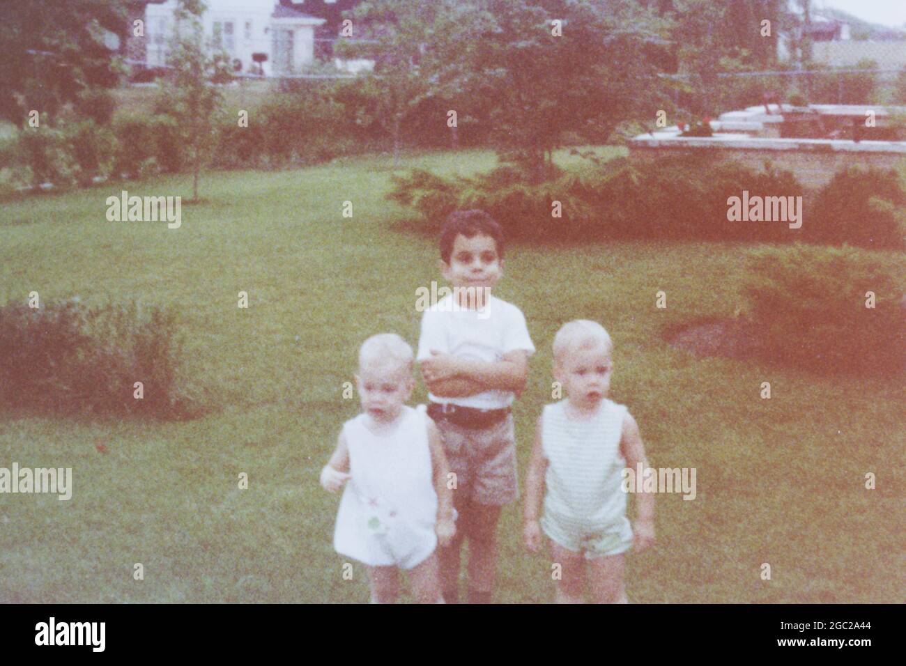 Ein altes Foto von drei Kindern, die für ein Foto im Hinterhof stehen. Stockfoto