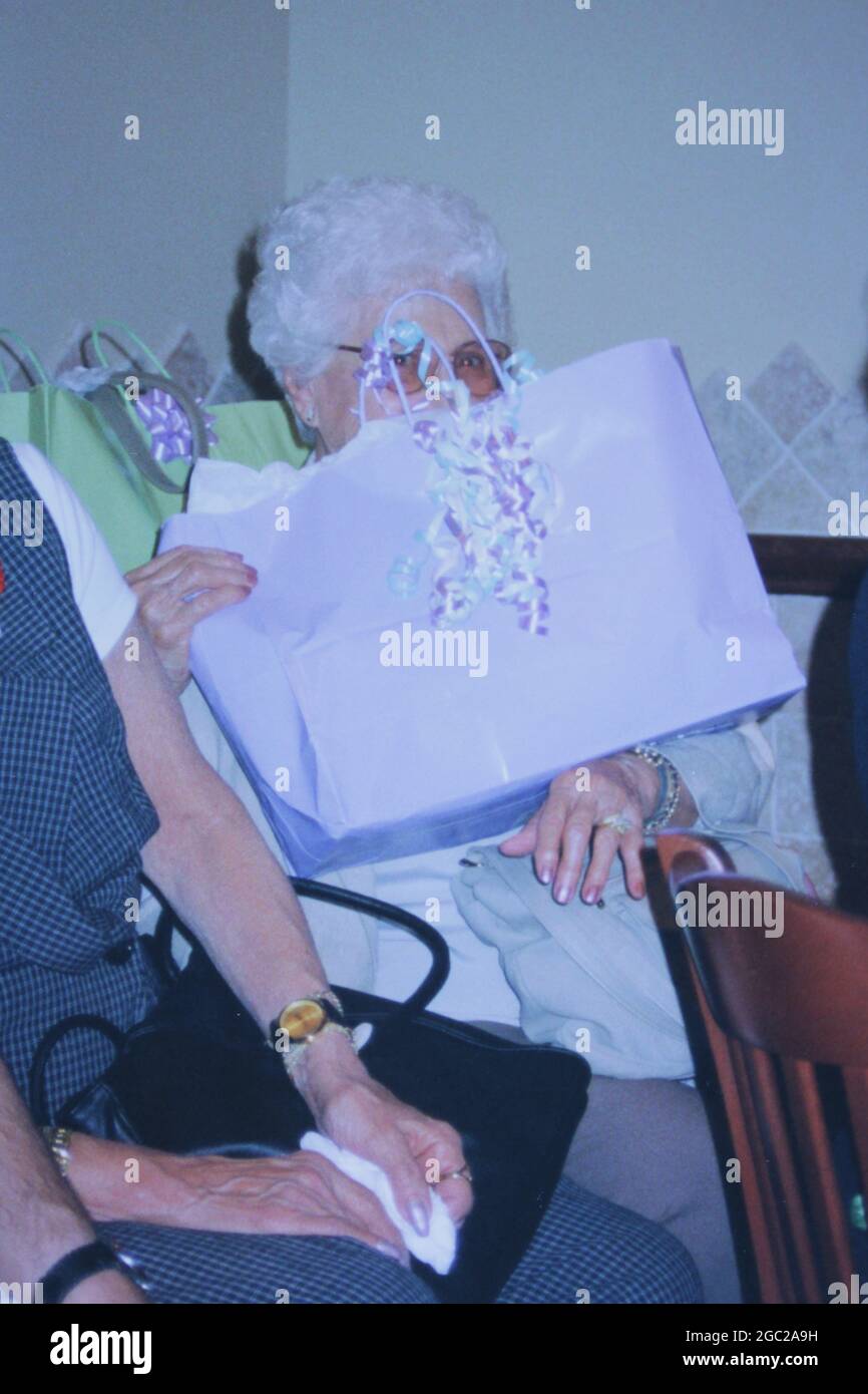 Ein altes Foto einer älteren Frau, die sich hinter einer Geschenktüte versteckt. Stockfoto