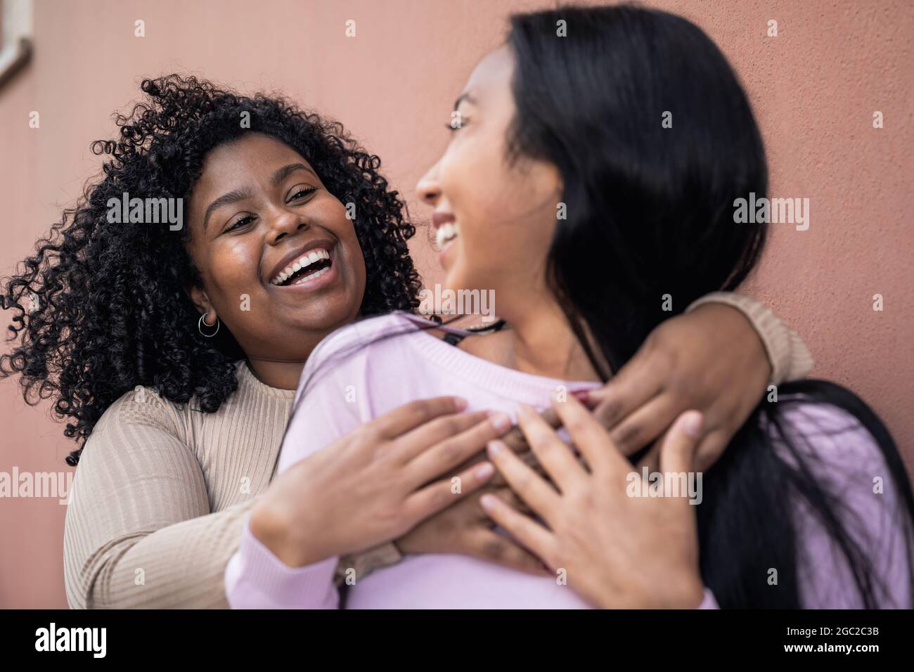 Happy Latin Mädchen mit Spaß Umarmung im Freien - Young People Lifestyle und Freundschaft Konzept Stockfoto