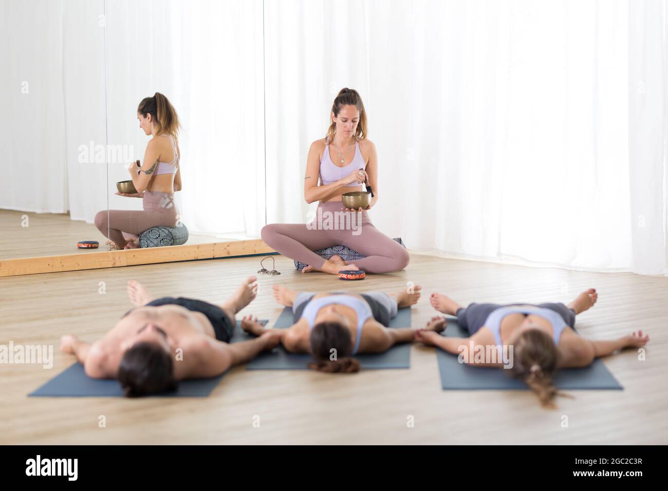 Yogalehrer und Gruppe junger sportlicher Menschen im Yoga-Studio, liegen und entspannen auf Yogamatten während der erholsamen Yoga-Sitzung. Gesund aktiv Stockfoto